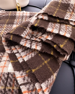 Close-up of thick plaid cashmere scarf with orange and brown textured tassels