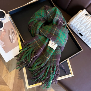 Detail of green and purple plaid cashmere-feel scarf with fringe and fabric brand label