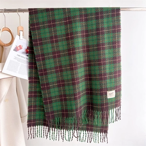 Detail of green plaid cashmere scarf featuring thick knit texture and long tassel edges