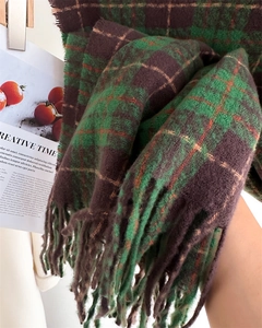 Close-up of thick green and brown plaid scarf featuring long fringes and textured knit fabric