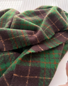 Macro shot of high-density brushed plaid fabric showing soft texture and tassel detail