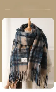 Detail of blue and brown checkered scarf featuring soft tassel edges and a brand woven label