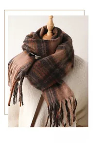 Close-up of brown plaid scarf featuring soft fringe edges and warm cashmere-like texture