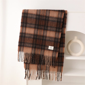 Close-up of warm plaid cashmere-like scarf with fringe detail and orange accents