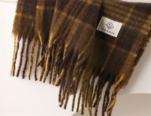 Macro detail of the thick plaid cashmere-like scarf texture with fringe and brand label