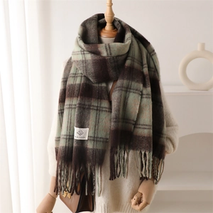 Close-up of retro plaid scarf with long tassels and branding label on soft knit fabric