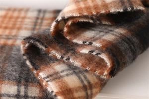 Detail of soft plaid scarf texture in orange and grey with thick warm cashmere-like fringe