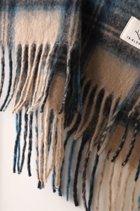 Macro detail of plaid scarf fabric showing soft brushed texture and fringe edges