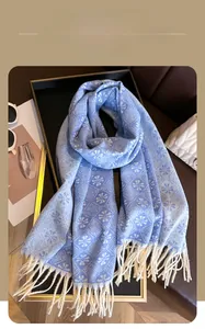 Detail of blue and white jacquard winter scarf with snowflake pattern and long white tassels