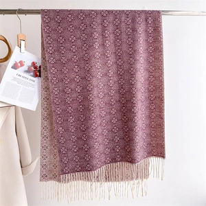 Close-up of jacquard scarf with geometric floral patterns and fringe tassels detail