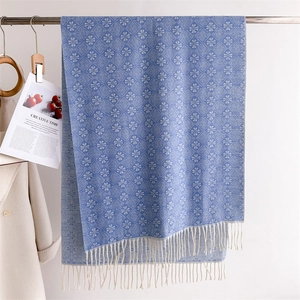 Detail of navy blue jacquard knit scarf with ivory geometric patterns and tassel fringe