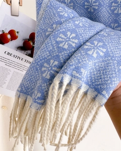 Detail of blue winter scarf with white snowflake jacquard pattern and soft fringe edges