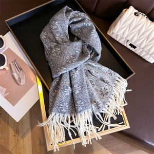 Detailed view of grey-blue cashmere-like scarf featuring white snowflake patterns and fringe