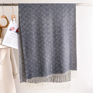 Detailed view of blue-gray jacquard scarf with snowflake pattern and fringe trim