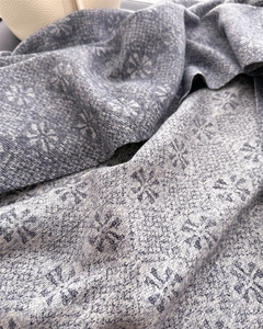 Detail of grey-blue jacquard knit scarf showing snowflake patterns and soft texture