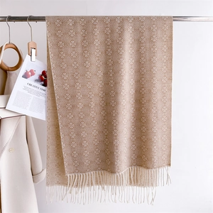 Detail of warm jacquard pashmina scarf with white floral patterns and soft cream tassels