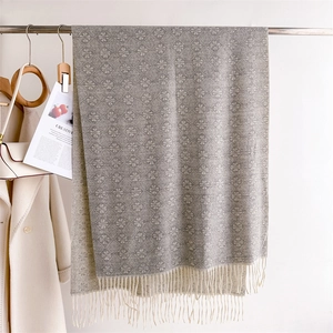 Macro detail of grey jacquard scarf with retro floral patterns and elegant fringe trim