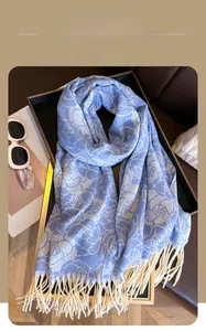 Detail of light blue floral scarf with long white tassels and soft knitted texture