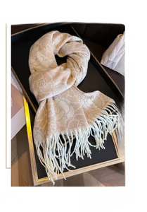 Close-up of elegant floral jacquard knit scarf with long decorative tassels on a tray