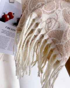 Close-up of elegant rose jacquard knit pattern and fringe tassels on a warm shawl scarf