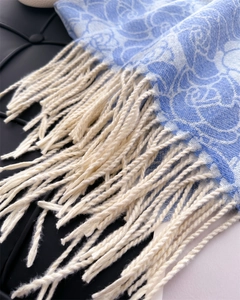 Close-up of blue floral cashmere-like scarf showing soft texture and white twisted tassels