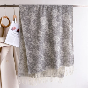 Detail of soft cashmere-like grey and white floral scarf with long fringe and knit texture