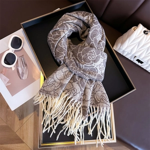 Detail of grey cashmere-like scarf with white floral prints and decorative long tassels