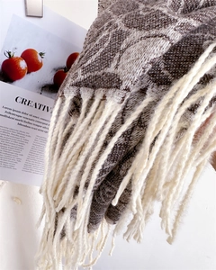 Close-up of tassel fringe detail on a warm jacquard scarf with letter pattern