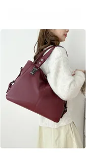 Détails du sac cabas bordeaux avec texture en cuir litchi et ornements métalliques