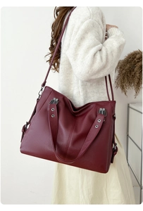 Sac fourre-tout bordeaux en cuir grainé avec rivets et bandoulière sur mannequin femme