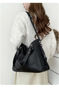 Détail d'un grand sac à main noir en cuir grainé porté par un mannequin en décor épuré