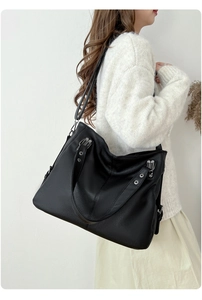 Détails du cuir grainé noir et des ferrures métalliques argentées sur un grand sac cabas