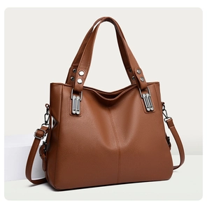 Détail d'un sac cabas en cuir marron grainé avec poignées renforcées et rivets argentés