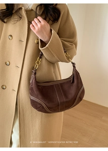 Détail du sac à épaule en daim marron foncé avec boucles dorées et coutures contrastées