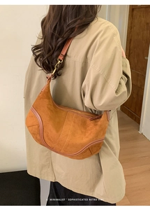 Sac hobo en daim caramel porté sur un trench beige pour référence de taille