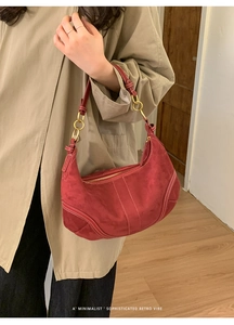 Détail du sac hobo bordeaux en daim avec surpiqûres blanches et anneaux métalliques dorés