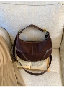 Détail du sac hobo en daim marron avec surpiqûres blanches et anneaux dorés