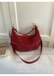 Détail du sac dumpling en daim bordeaux avec coutures contrastées et anneau en métal doré