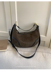Détail du sac Hobo en daim marron foncé avec bordures en cuir noir et surpiqûres blanches
