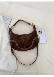Détail du sac demi-lune en daim marron avec surpiqûres blanches et chaîne dorée chic
