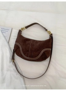 Gros plan d'un sac hobo rétro en daim marron foncé avec surpiqûres et boucles dorées