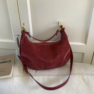 Sac bandoulière demi-lune bordeaux en daim avec surpiqûres blanches et décor boisé