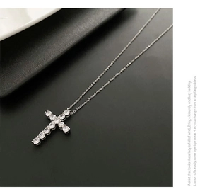 Detail of silver cross necklace featuring sparkling round zircon stones on black background