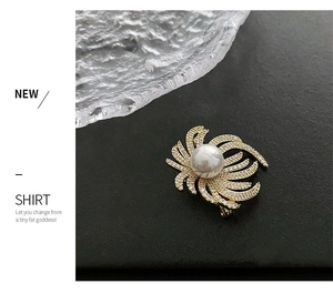Detail of luxury copper lapel pin featuring a large pearl and zircon crystals on black backdrop