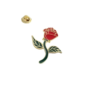 Artistic red rose enamel brooch with golden metal edges and green leaves on white background