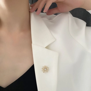 Élégante broche fleur marguerite avec perles et métal doré sur revers de blazer