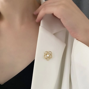 Élégante broche camélia dorée avec perles sur le revers d'une veste de tailleur blanche