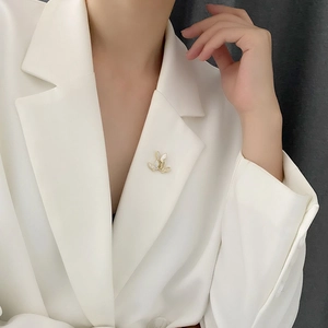 Elegant gold butterfly brooch with white shell wings pinned on a white blazer lapel