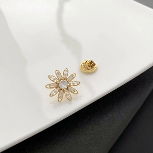 Broche fleur marguerite élégante avec zircons et perles sur une monture en métal doré