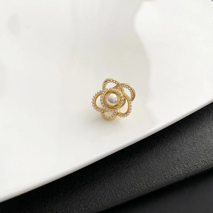Broche camélia dorée élégante avec perles sur plateau blanc pour décor de costume